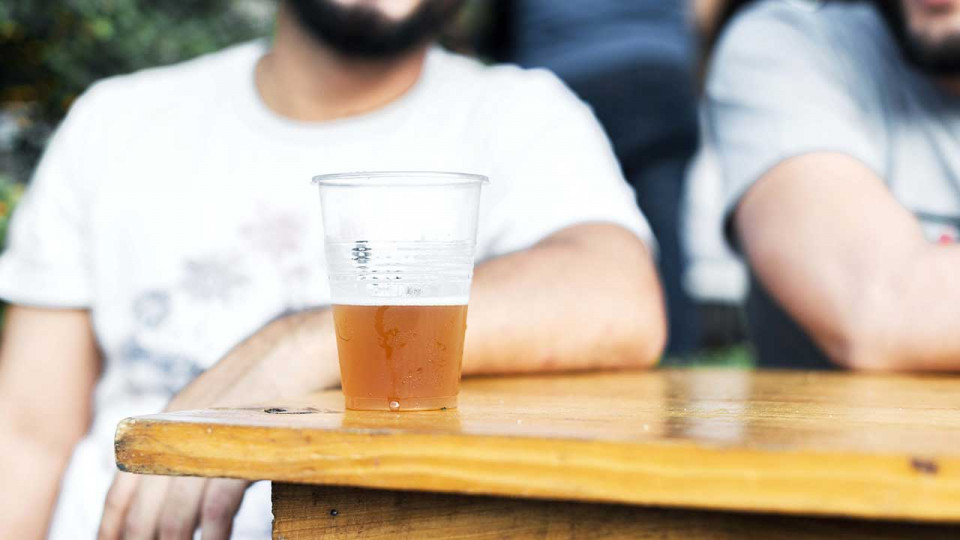 cup of beer on table with people having a great time in the background